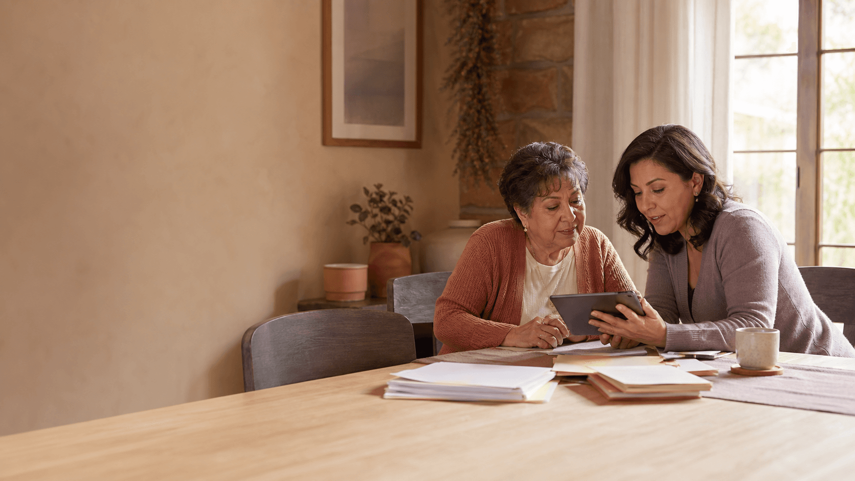 A Hispanic adult daughter in conversation with her parent at a dining room table